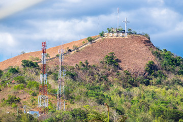 The sign of the city of Coron is on a hill, a famous tourist viewpoint. Catholic cross on a hill, mountain in the town of Coron, Philippines, Palawan Busuanga. Travel concept.