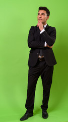 Obraz na płótnie Canvas Young handsome Hispanic businessman against green background