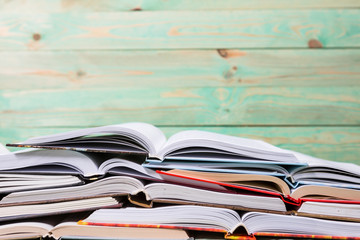 Stack of open books pile of various books on wooden background. With copy space for your text
