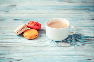 Cup of coffee with macarons on a blue wooden background. Selective focus.