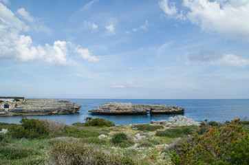 Fototapeta na wymiar Photograph of a landscape of Menorca with a natural bridge in the middle of the sea. Rocks, water and plants.