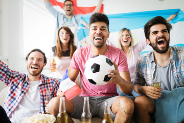 Soccer fans emotionally watching game in the living room.