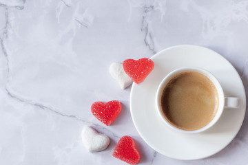 cup of coffee with marmalade in the shape of a heart on a marble background. Copy spase. Top view
