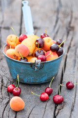 Rustic  country still life with summer fruits (cherries and apricots) in a blue  old colander on an antique wooden table