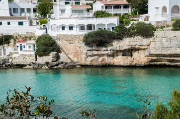 Fototapeta na wymiar Photograph of a beautiful landscape of Menorca with its characteristic white houses and crystal clear waters with a turquoise blue.