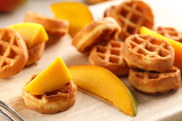 circle mini waffles with mango on wooden cutting board