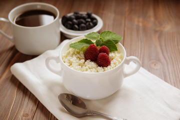 Russian cottage cheese with berry and mint, blueberries and coffee on wooden table.