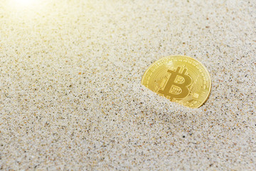 coin bitcoin buried in the sand. Bitcoin is the most popular cryptocurrency in the world.