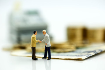 Miniature people : businessman talking and hand shake on stack of coins money with minihouse,Business finance concept.