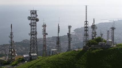 aerial view of telecom antennas telecommunications towers on mountaintop and cityscape in background