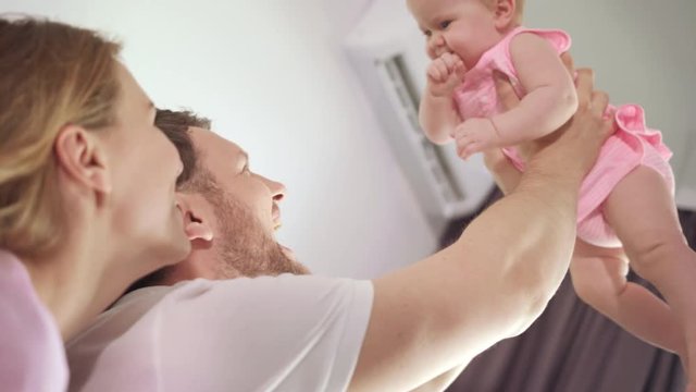 Happy father holding baby on hands. Sweet family love. Happy parents holding baby in air at home. Togetherness love. Bearded dad carrying child. Joyful baby in father embrace. Happy family love child