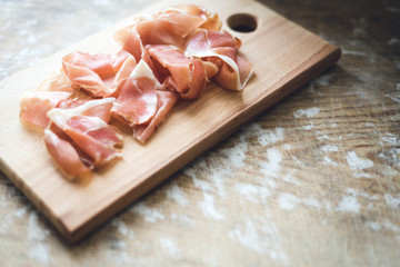 Prosciutto on wooden background