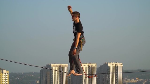 The man is engaged in extreme sports of highline