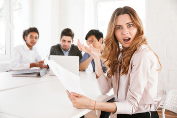 Shocked young woman holding documents