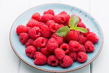 Fresh raspberries in a plate on a  vintage background.