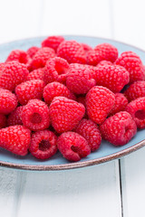 Fresh raspberries in a plate on a  vintage background.