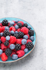 Fresh berry salad on blue dishes. Vintage wooden background.