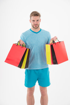 Man with shopping bags isolated on white. Macho with colorful paper bags. Fashion shopper in casual blue tshirt and shorts. Holidays preparation and celebration. Shopping during sale and black friday