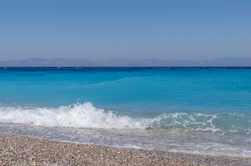 Summer close up of small wave and sand pebble beach with bubbles