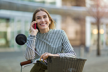 Fototapeta premium Young woman On Bike Using Mobile Phone