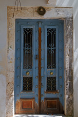 Worn blue wooden door with wrought iron and glass in an old building in Fiskardo on the Greek island Cephalonia