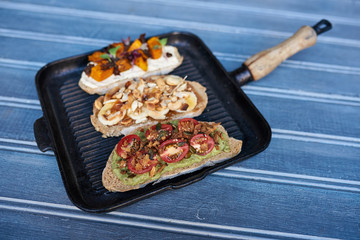 Frypan full of open faced sandwiches on a blue table