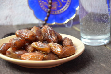 A glass of drinking water and date fruits - a food that is consumed before breaking fast during...