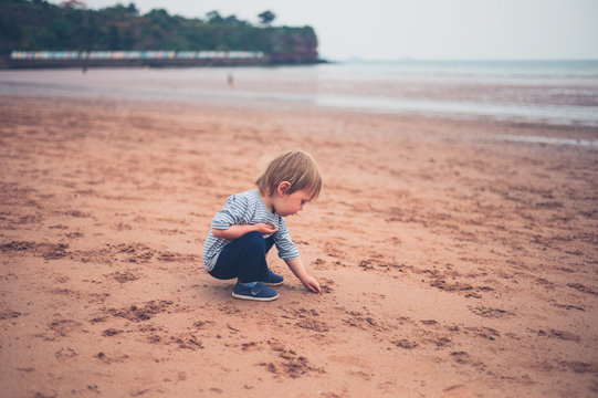 Little toddler boy sititng on beach