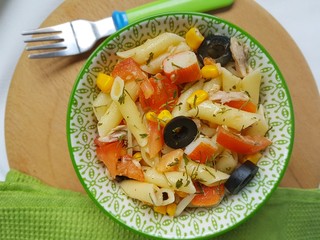  Top view, pasta salad with tomato, corn and black olives