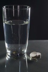 Glass of water and pills isolated on white