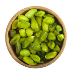 green shelled pistachio in wooden cup isolated on white background. top view