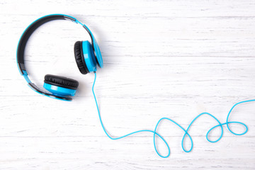 Blue headphones on wooden background, top view