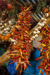 Dry garlic, red chilly pepper, herbs, spices and greens hanging under roof on local food market in asian, middle east or caucasian country.