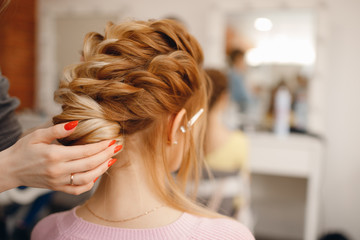 Close-up of woman hairdresser weaving plaits in beauty salon.