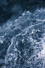 Surface of the sea with waves,  splash,  foam and bubbles at high tide and surf, blue abstract background