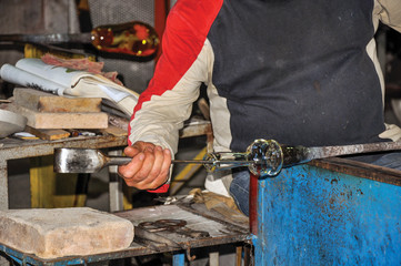 Detail of craftsman hands working on glass sculpture in a Murano workshop, a small and pleasant town on top of islands near Venice. Located in the Veneto region, northern Italy
