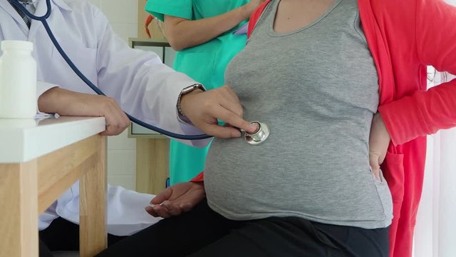 doctor with stethoscope listening to pregnant woman baby heartbeat at hospital