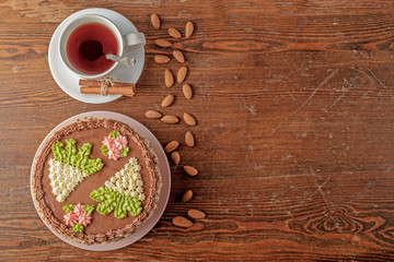 Homemade Kiev cake, cup of tea and scattered almonds on old wooden surface of table. The known ukrainian delicacy. Copy space for text, top view.