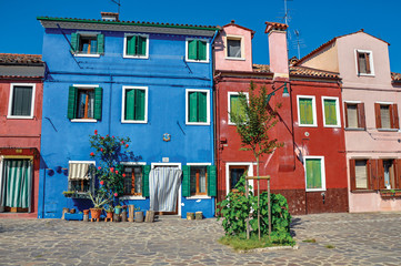 Fototapeta na wymiar Overview of colorful terraced houses on sunny day in Burano, a gracious little town full of canals, near Venice. Located in the Veneto region, northern Italy