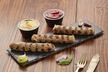 Grilled Veal minced meat with spices on black stone and wooden background 