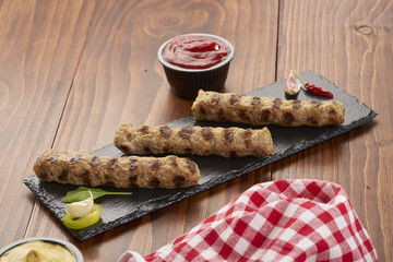 Grilled Veal minced meat with spices on black stone and wooden background 