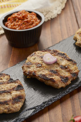 Grilled Veal minced meat with spices on black stone and wooden background 