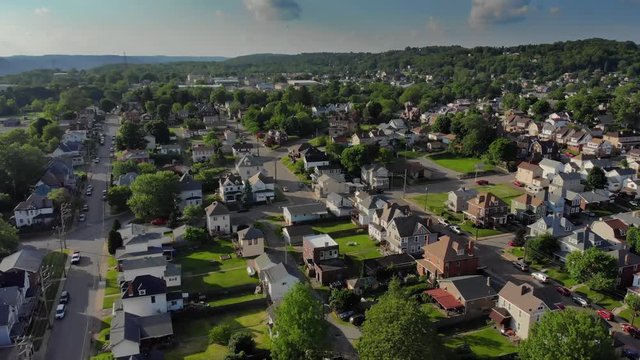 A slow forward aerial establishing shot of a residential neighborhood in a small Pennsylvania town at sunset. Pittsburgh suburbs.  	
