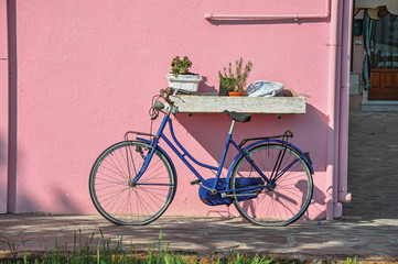 Fototapeta na wymiar Close-up of bicycle leaning against colorful wall on a sunny day in Burano, a gracious little town full of canals, near Venice. Located in the Veneto region, northern Italy