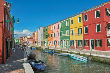 Panoramic view of colorful buildings and boats in front of a canal, in a sunny day at Burano, a gracious little town full of canals, near Venice. Located in the Veneto region, northern Italy