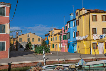 Overview of colorful buildings and clothes hanging in a blue sunny day, in front of a canal at Burano, a gracious little town full of canals, near Venice. Located in the Veneto region, northern Italy