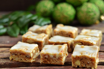 Square pieces of cake with nuts. Pieces of cake topped with icing on a wooden background