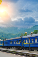 Train at the station in the background of the mountains and in the sun. The sky with rain clouds. Yaremche, Carpathians, Ukraine.