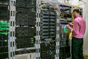 A specialist with optical Internet wires works in the server room. The system administrator...