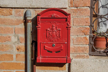 Close-up of a red post box stuck in a brick wall in the sunset at the city of Venice, the historic and amazing marine city. Located in the Veneto region, northern Italy
